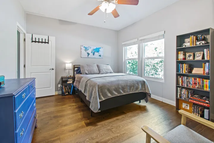 Wood-finish flooring, white walls, and a ceiling fan with integrated lighting