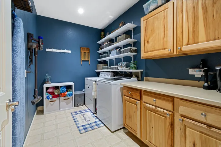 Laundry area with built-in wood cabinetry, light-toned countertop, and open shelving