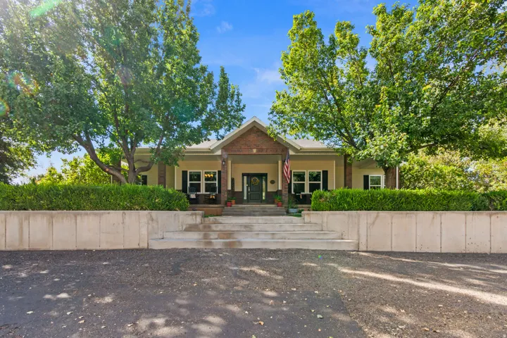 Front exterior featuring a covered porch, brick accents, and a concrete retaining wall with integrated steps