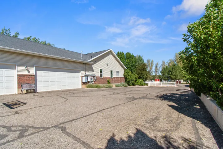 Exterior featuring multiple garage doors, brick veneer detailing, and a paved driveway