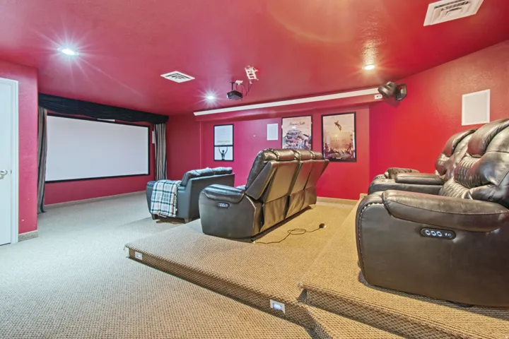 Dedicated media room featuring a large projection screen, recessed lighting, and integrated audio speakers