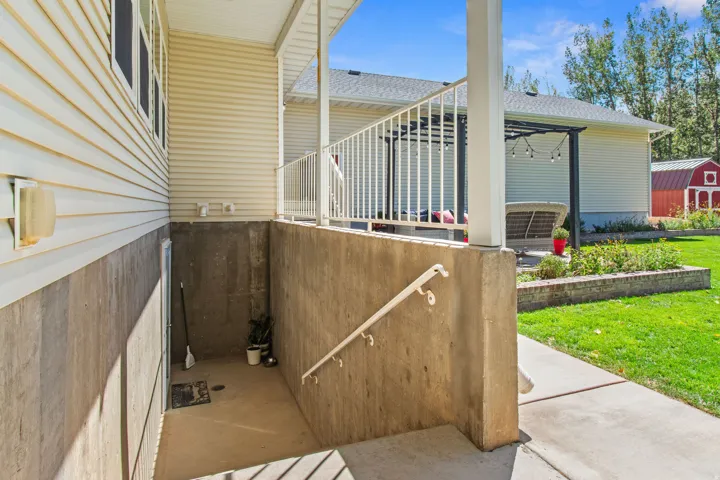 Exterior with light-colored siding, concrete foundation, and an outdoor patio featuring a pergola