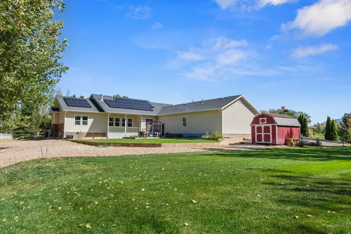Expansive backyard featuring a manicured lawn, gravel patio, and a red shed