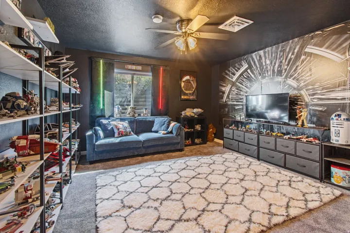 Ceiling fan with integrated lighting, built-in shelving, window with dark blinds, and a wall-mounted mural