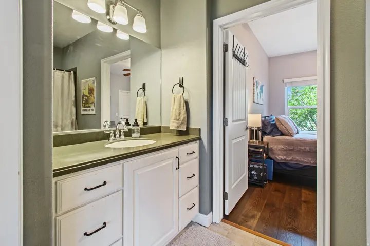 Vanity with integrated sink, chrome faucet, white cabinetry, and wall-mounted lighting