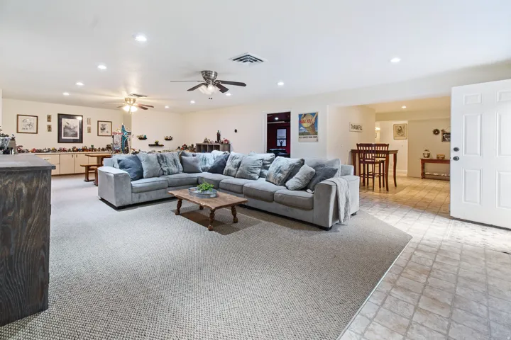 Expansive living area with recessed lighting and ceiling fans