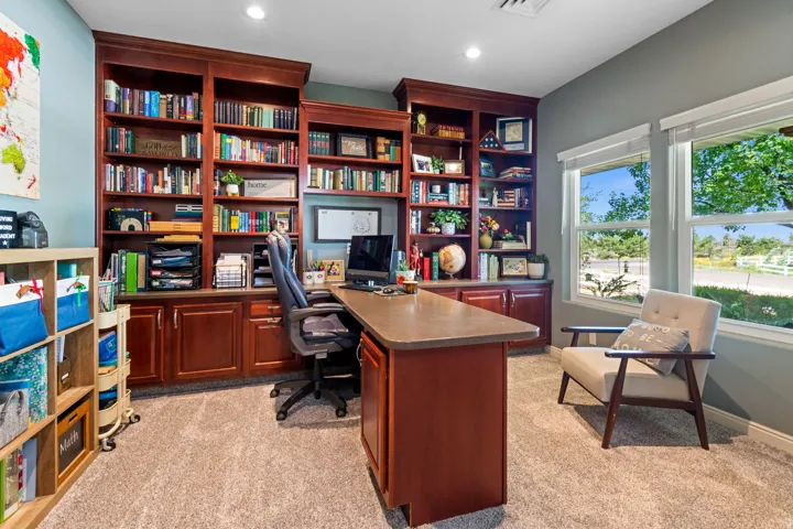 Built-in custom cabinetry with extensive shelving, dual windows providing ample natural light, and plush carpeting throughout