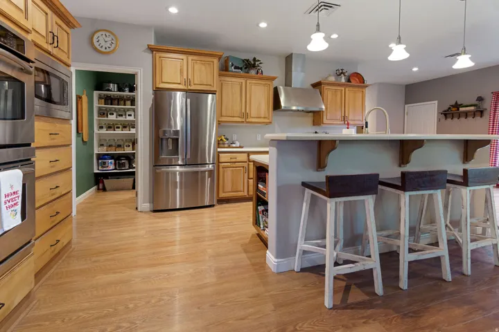 Wood-finish flooring, stainless steel appliances, recessed lighting, and a kitchen island with seating