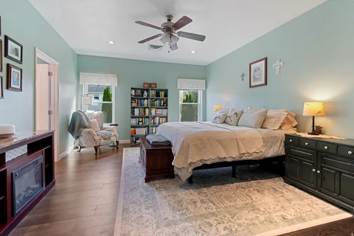 Hardwood-style flooring, a ceiling fan with integrated lighting, recessed lighting, and dual windows with privacy coverings