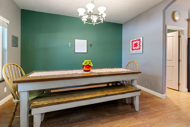 Wood-finish flooring, accent wall, ceiling-mounted light fixture, white trim, and a doorway with an arched opening