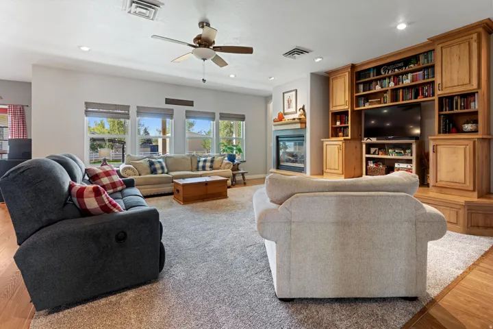 Built-in entertainment center with extensive shelving, fireplace with a mantel, recessed lighting, and wood-finish flooring