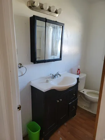 Black vanity with an integrated white sink, chrome faucet, and wood-finish flooring