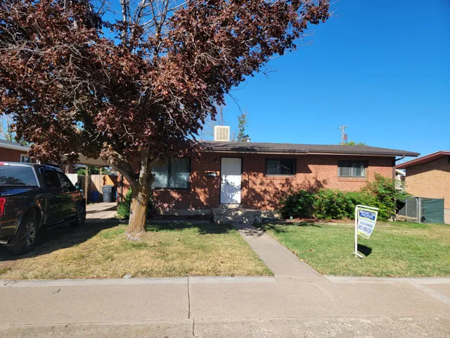 Brick exterior, front yard with mature tree, concrete walkway, and covered carport
