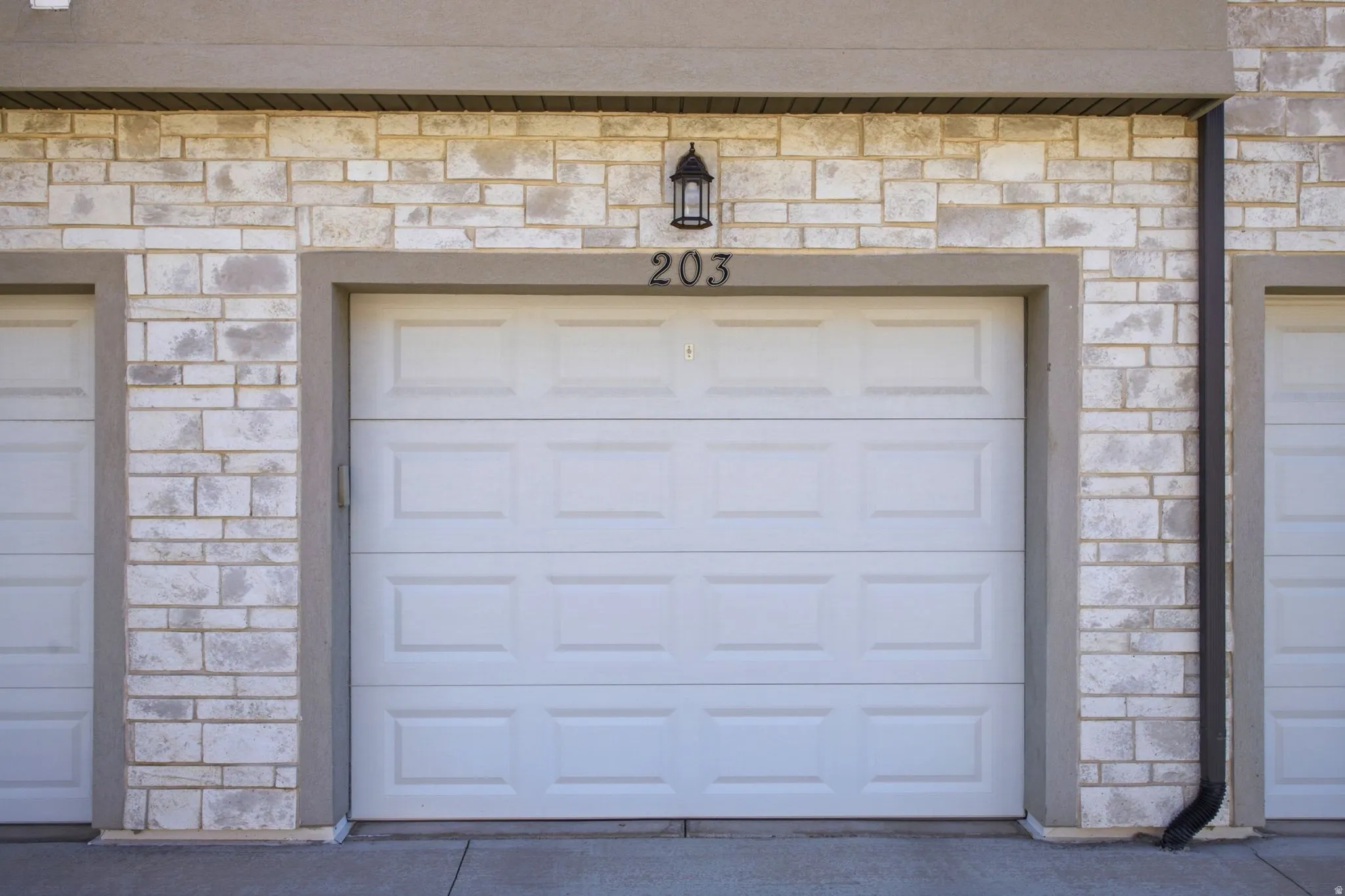 White paneled garage door framed by stucco trim