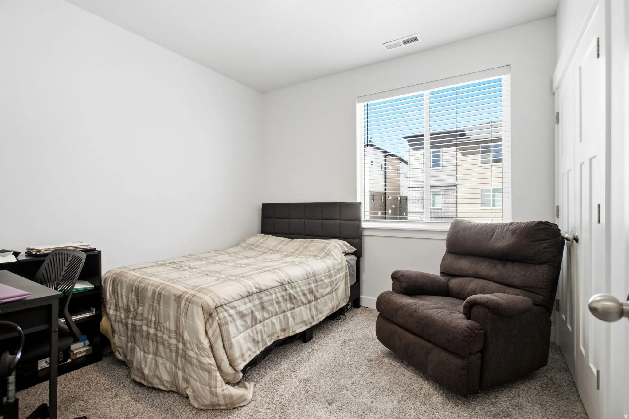 White walls, gray carpet, and a window with horizontal blinds