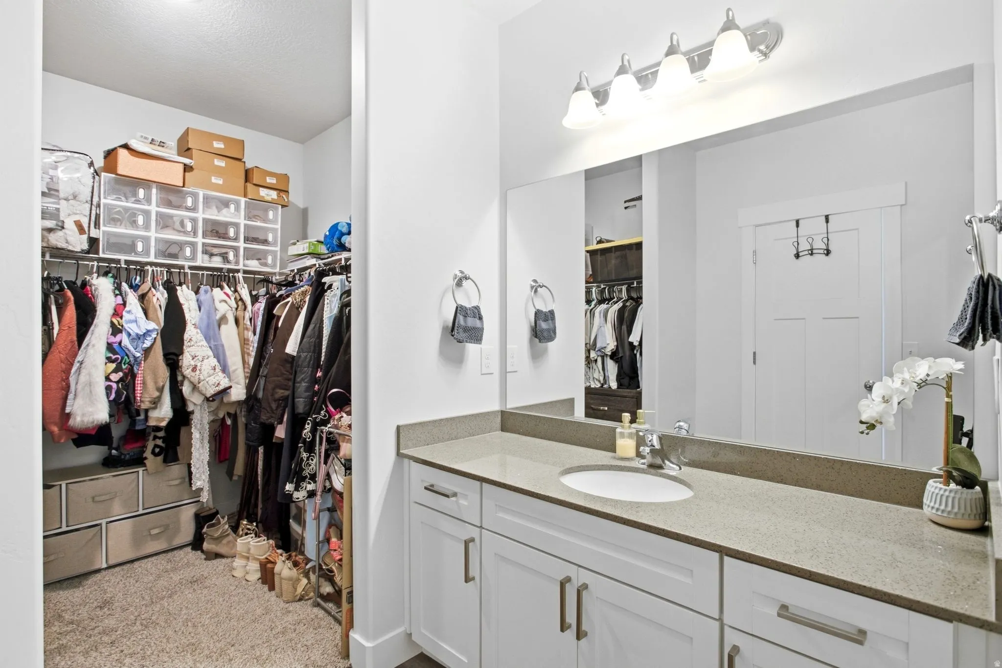 White vanity with brushed nickel hardware, light-colored countertop, undermount sink, and a large mirror