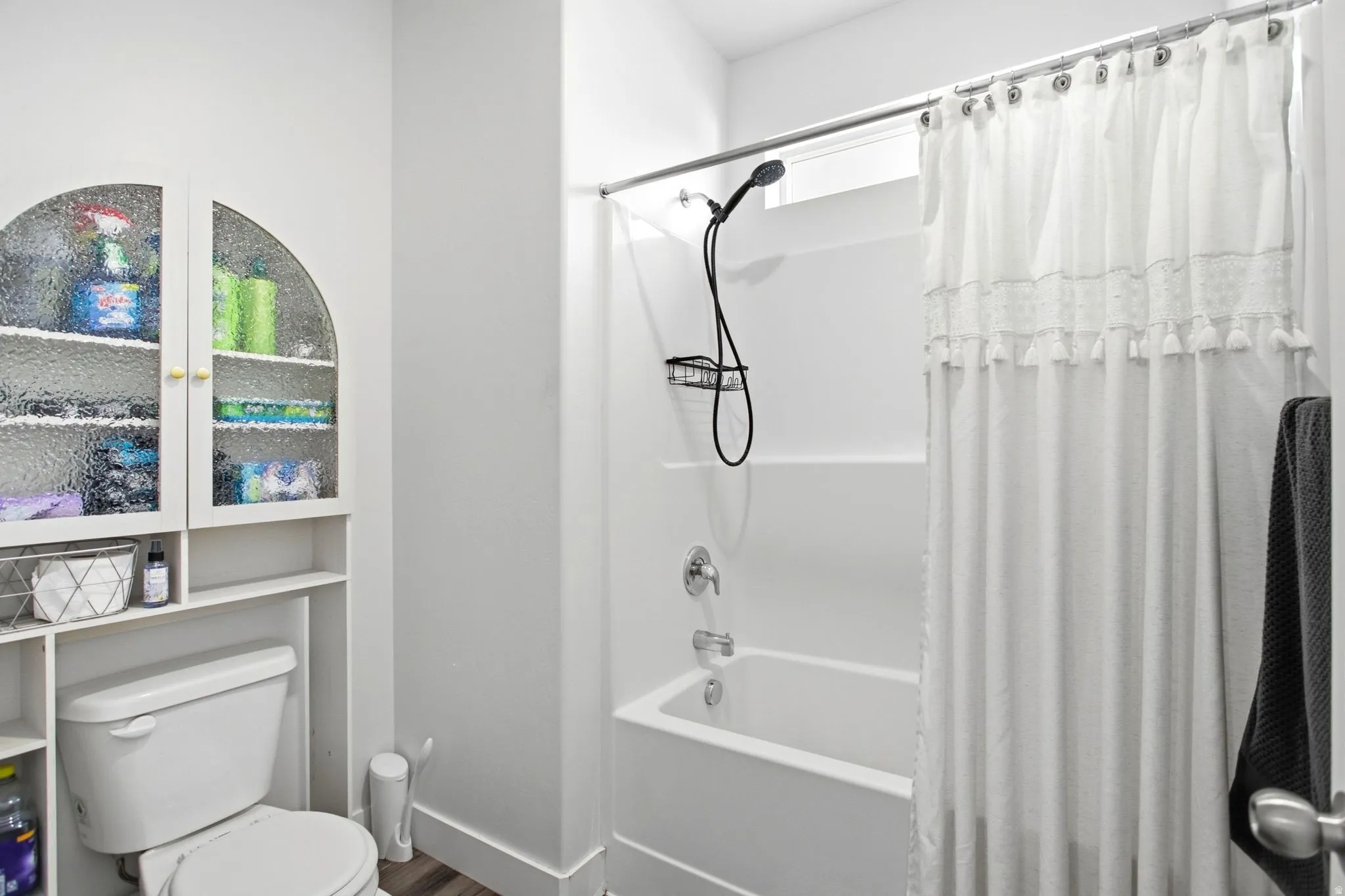 White bathtub and shower combination with a black shower head and chrome fixtures