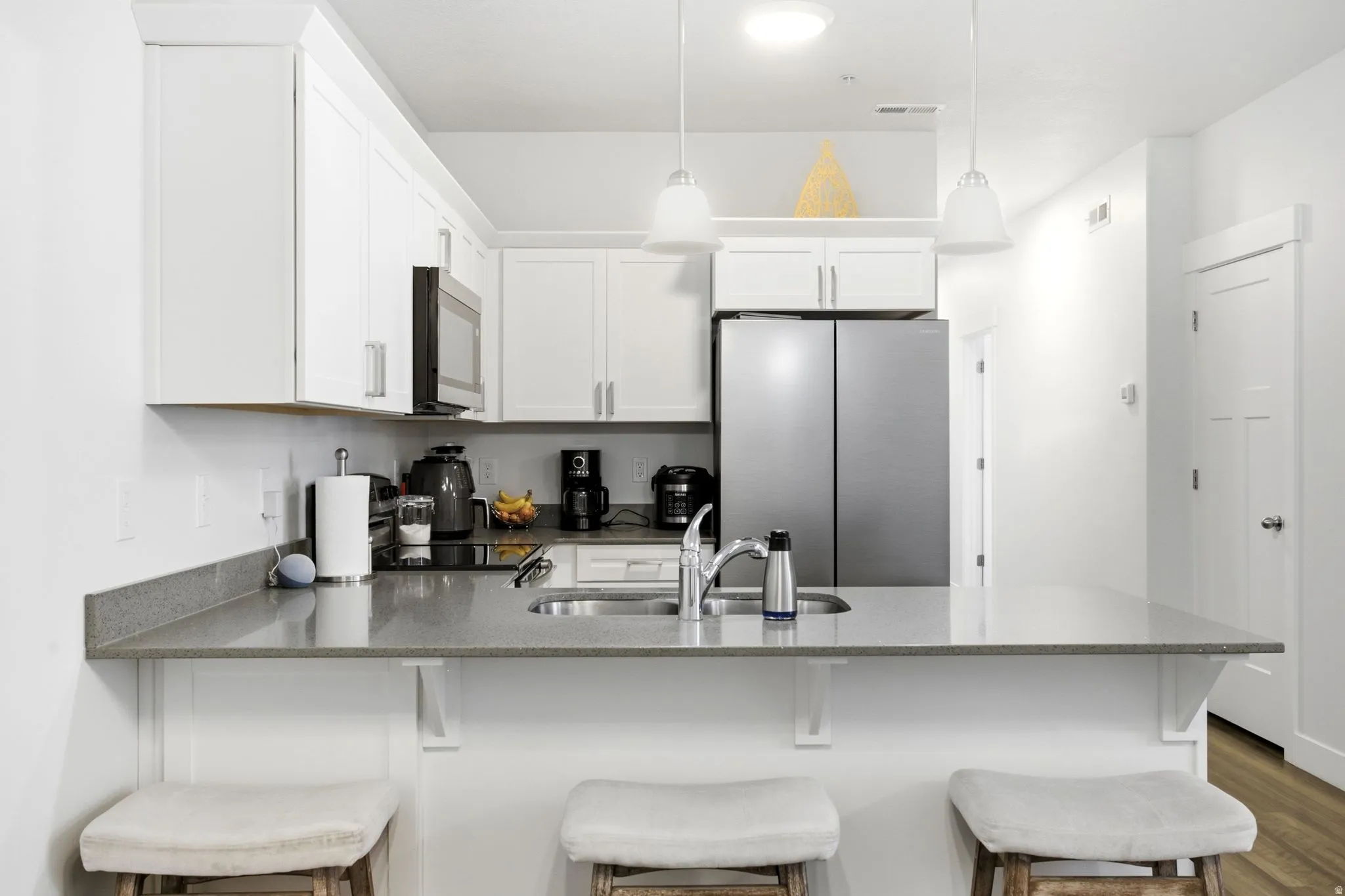Full kitchen with white cabinetry and stainless steel appliances, featuring a counter-depth refrigerator and built-in microwave