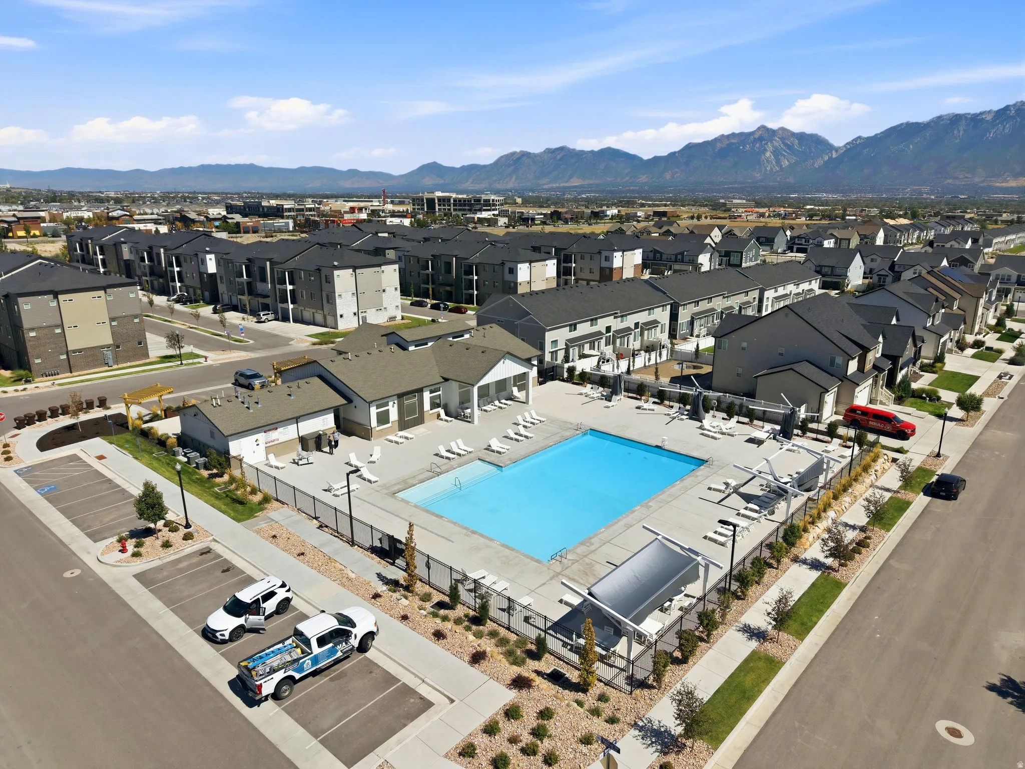 Community pool with surrounding lounge areas, established landscaping, and mountain backdrop