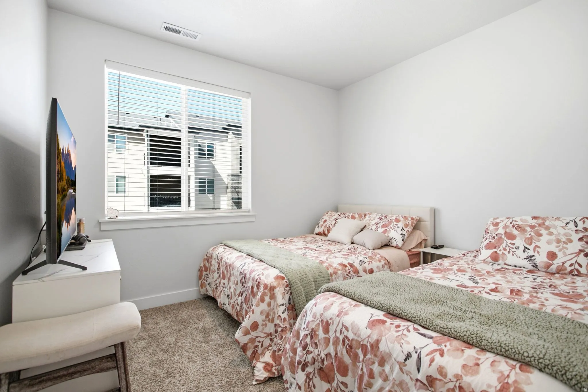 Carpeted flooring, white walls, and a window with blinds