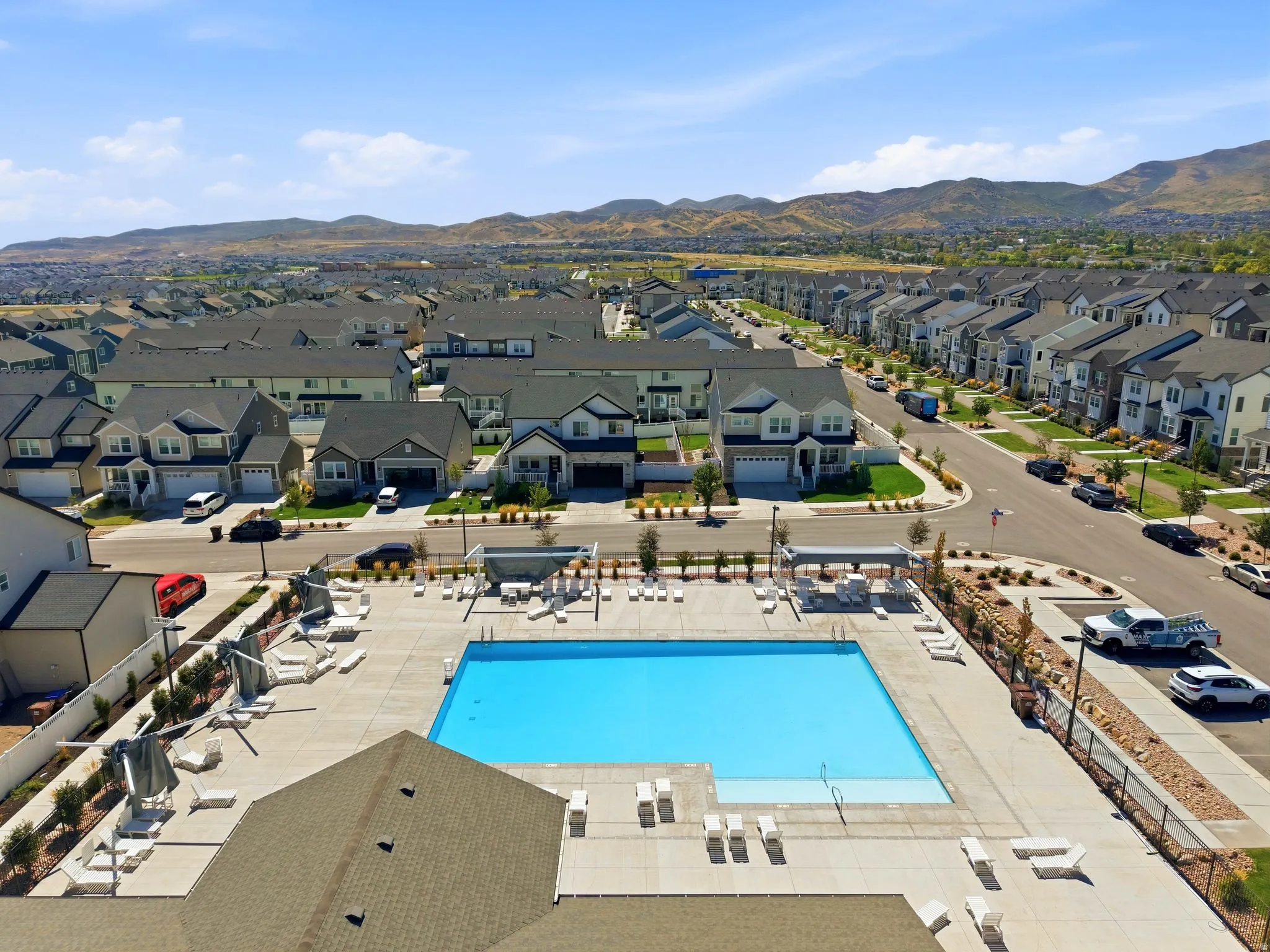 Community swimming pool with surrounding concrete decking, shaded lounge areas, and adjacent residential streets