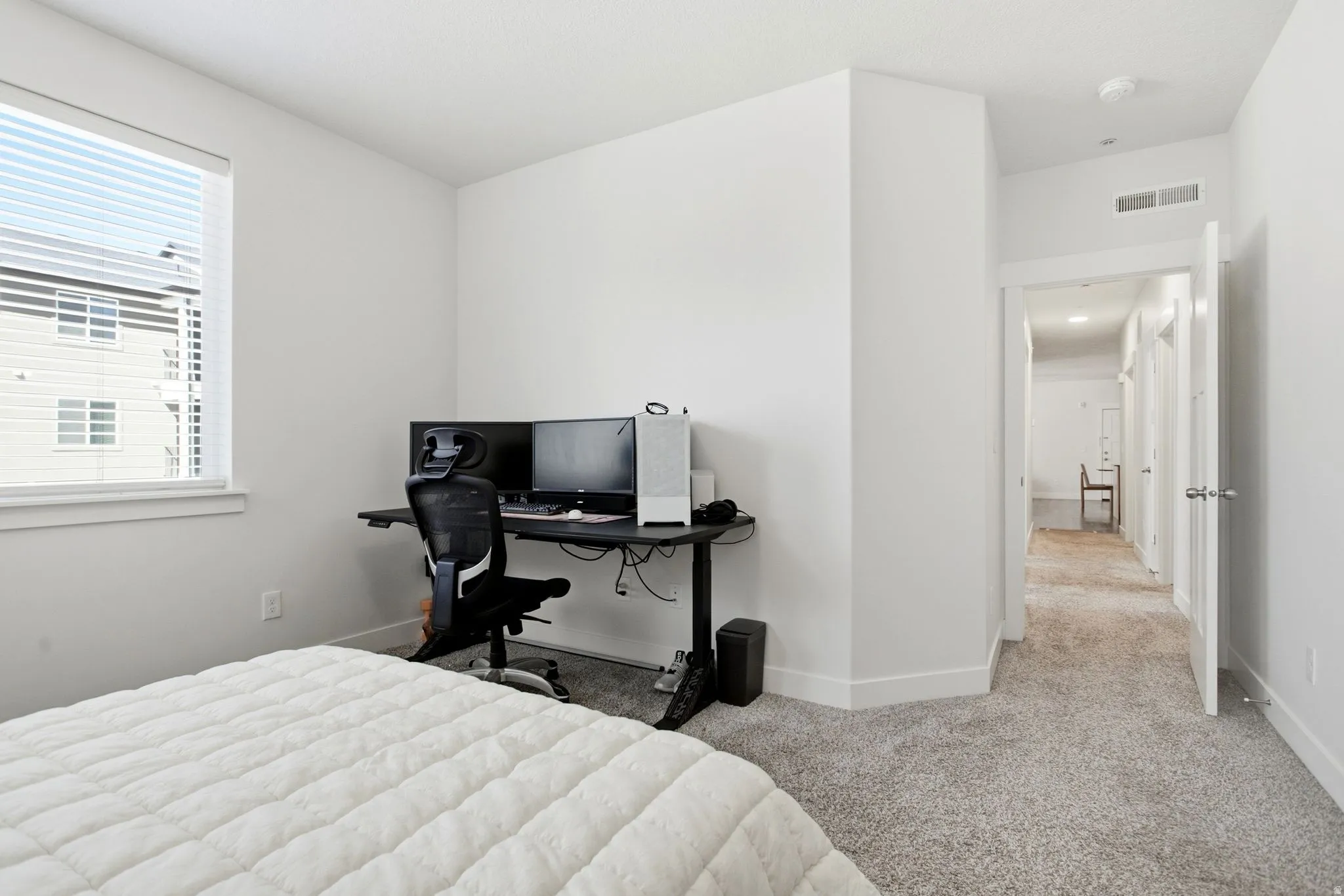 Window with horizontal blinds, light-colored walls, and gray carpet