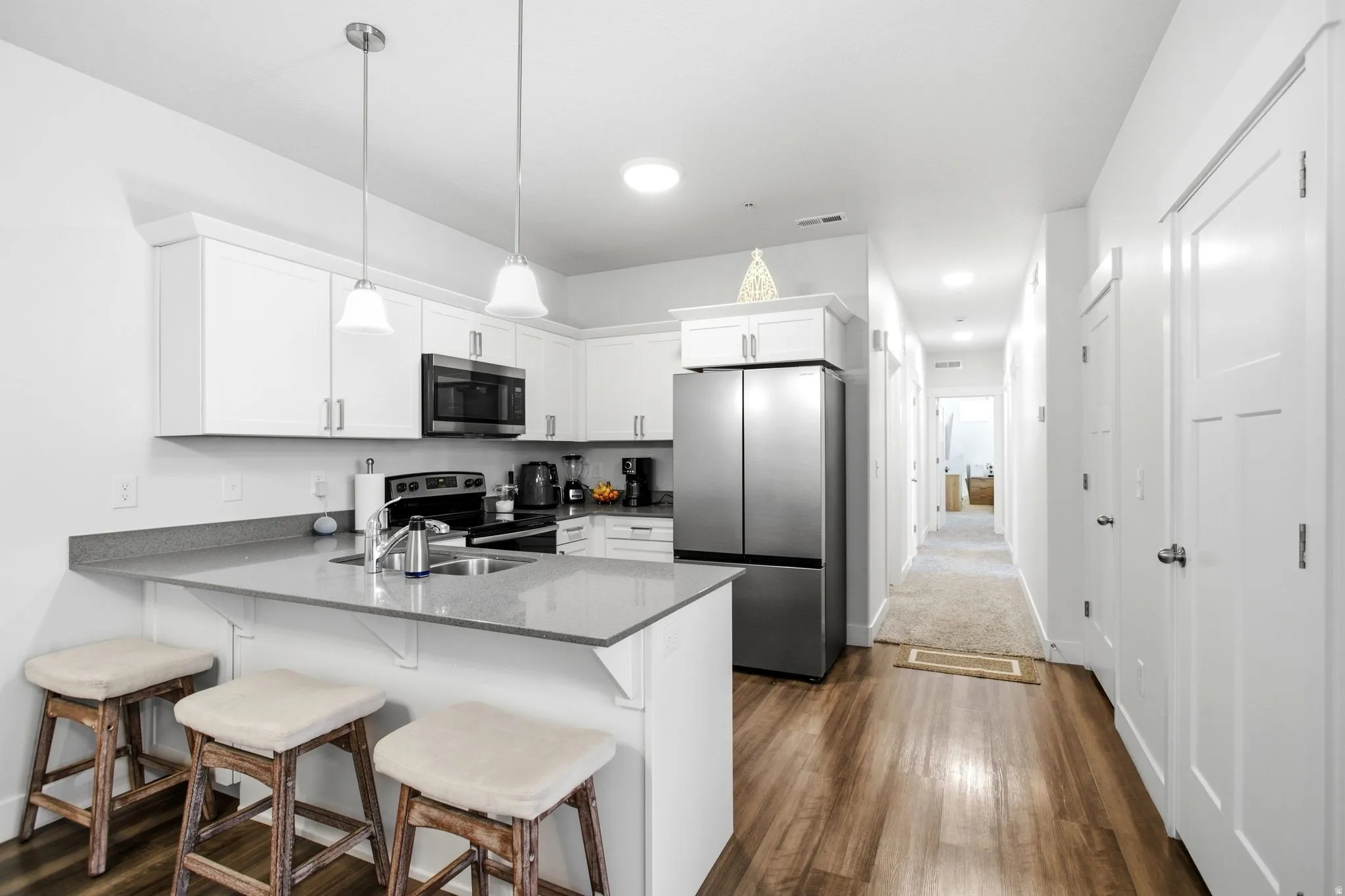 Kitchen featuring white cabinetry, gray countertops, stainless steel appliances, and wood-finish flooring