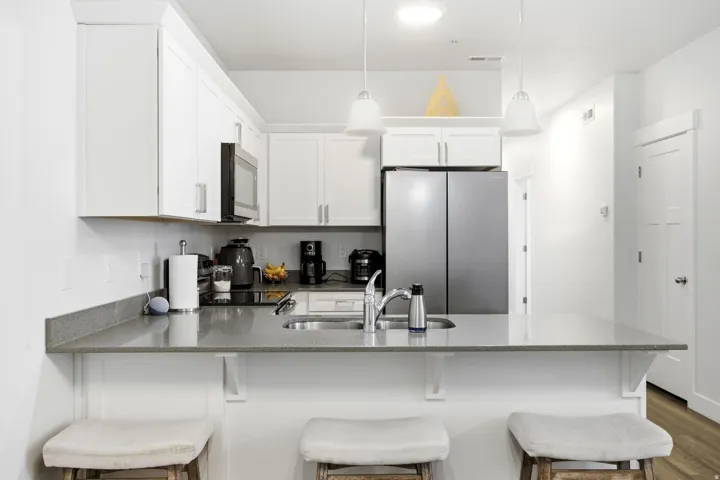 Full kitchen with white cabinetry and stainless steel appliances, featuring a counter-depth refrigerator and built-in microwave