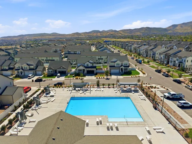 Community swimming pool with surrounding concrete decking, shaded lounge areas, and adjacent residential streets