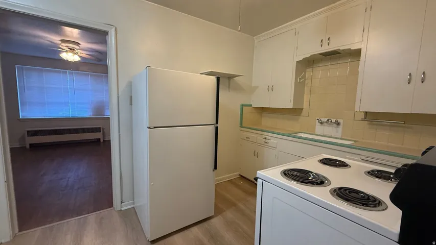 Kitchen featuring white cabinetry, tile backsplash, laminate countertops, and a white electric range