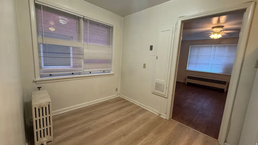 Wood-finish flooring throughout, bright window with blinds, and white painted walls
