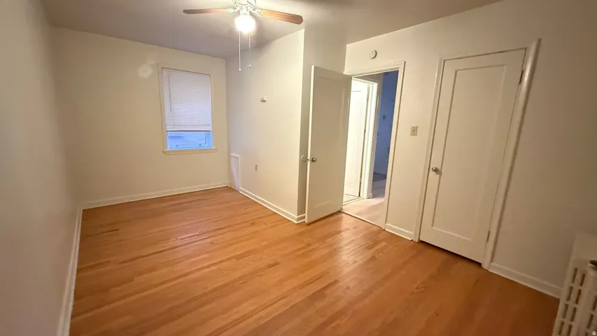 Wood-finish flooring, ceiling fan with integrated lighting, and white trim