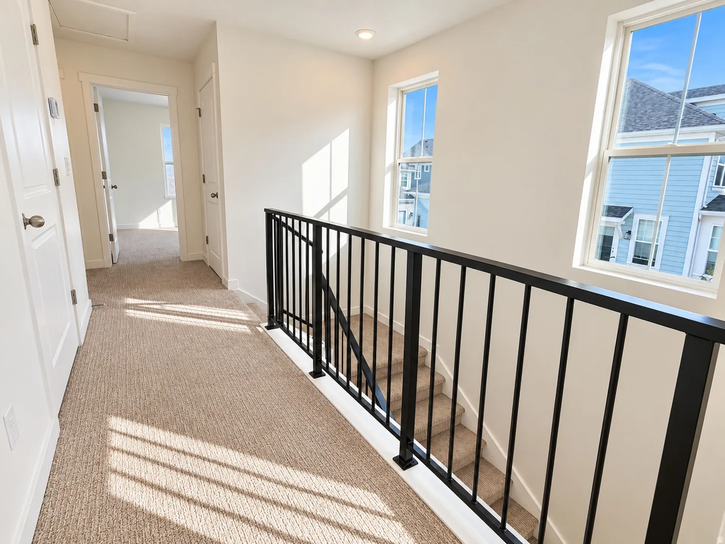 Upstairs hallway with metal railing and end unit windows