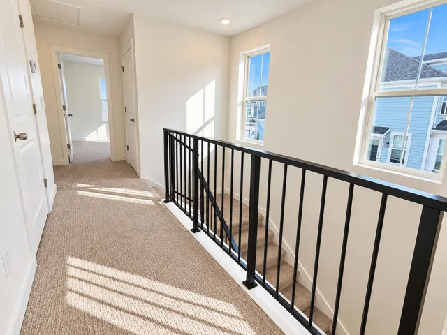 Upstairs hallway with metal railing and end unit windows
