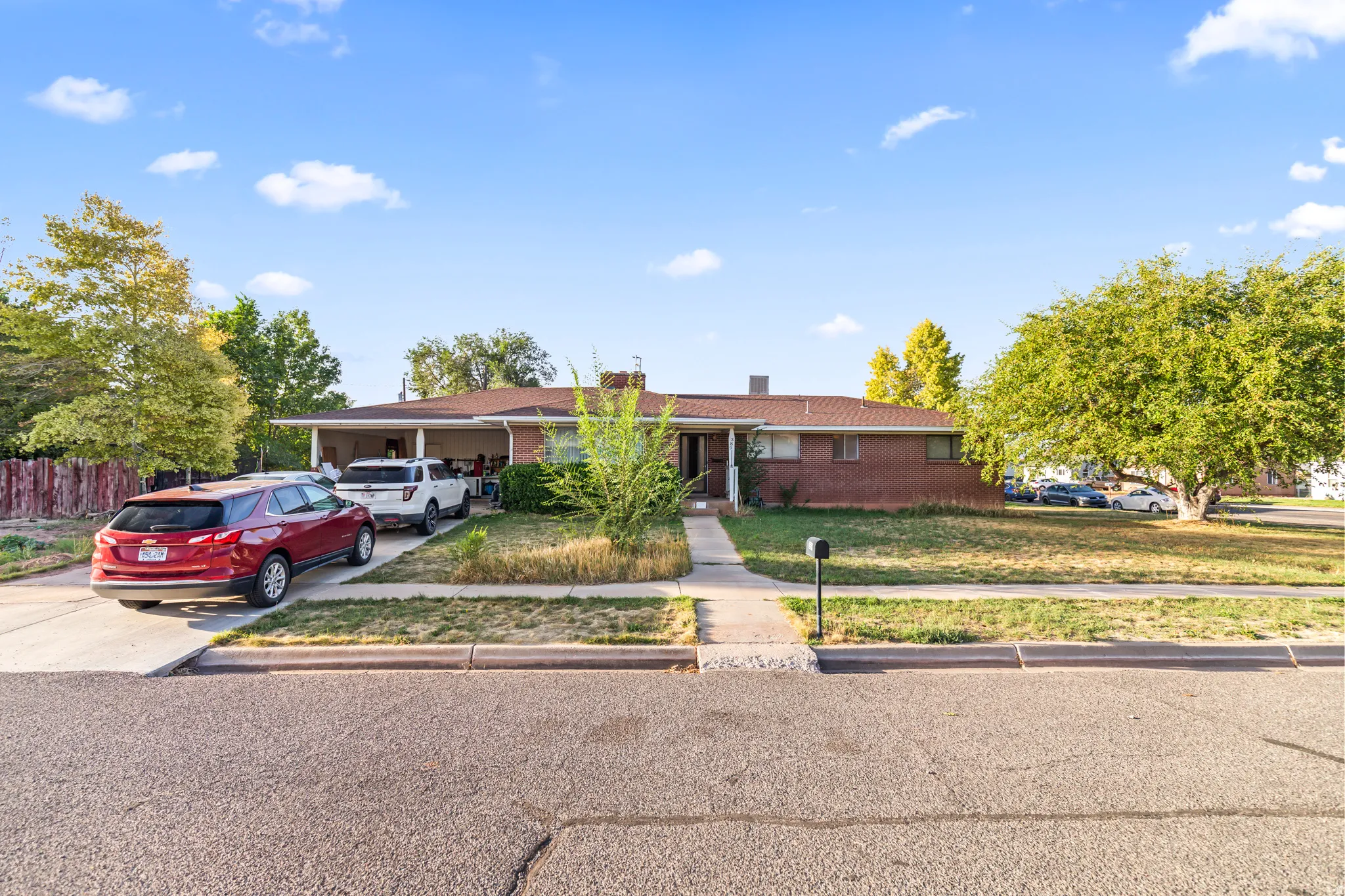 Brick exterior with a covered front porch, concrete driveway, and established front yard landscaping