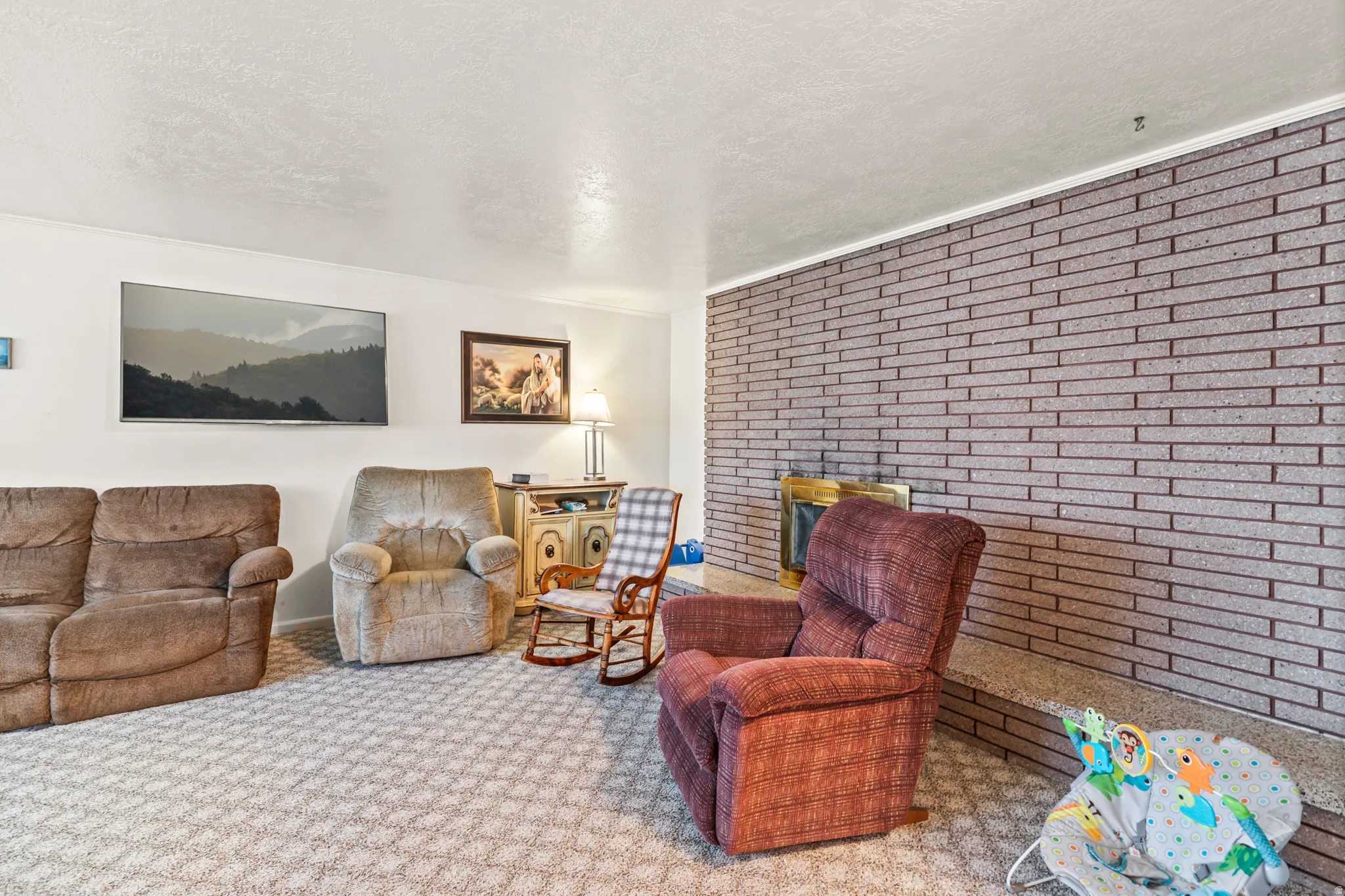 Brick fireplace with a brass firebox, wall-to-wall carpeting, and white painted walls