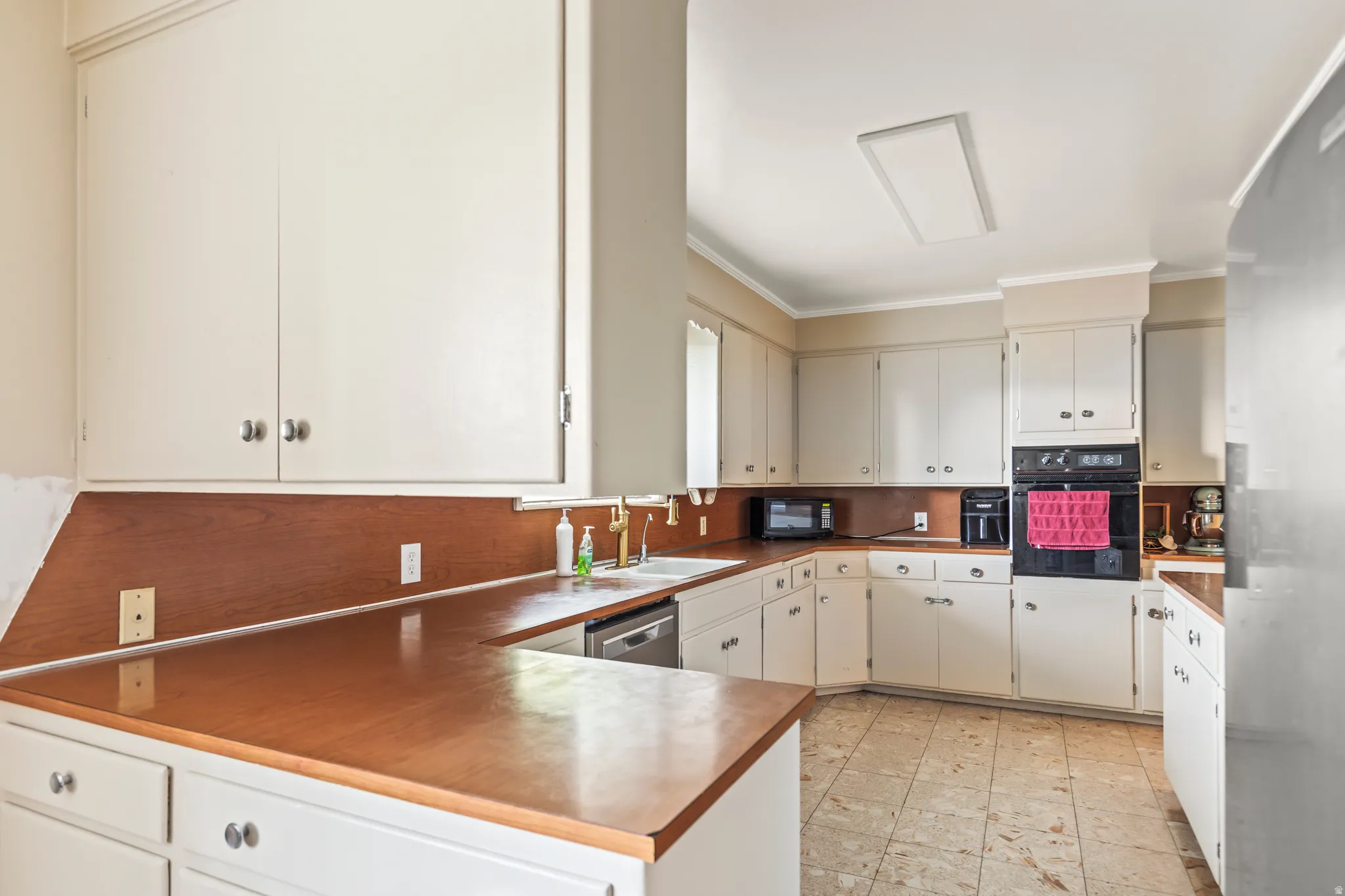 U-shaped kitchen with wood-finish countertops, white cabinetry, and built-in wall oven