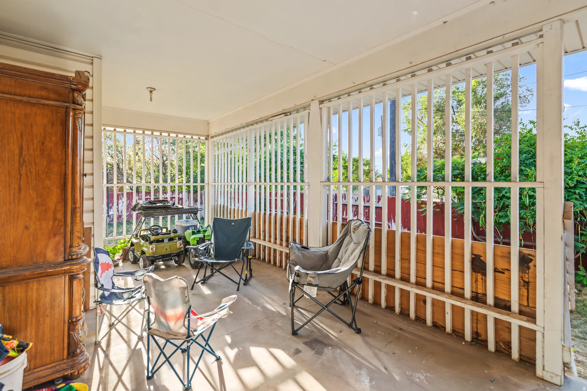 Covered outdoor patio with slatted wood railing and a concrete floor