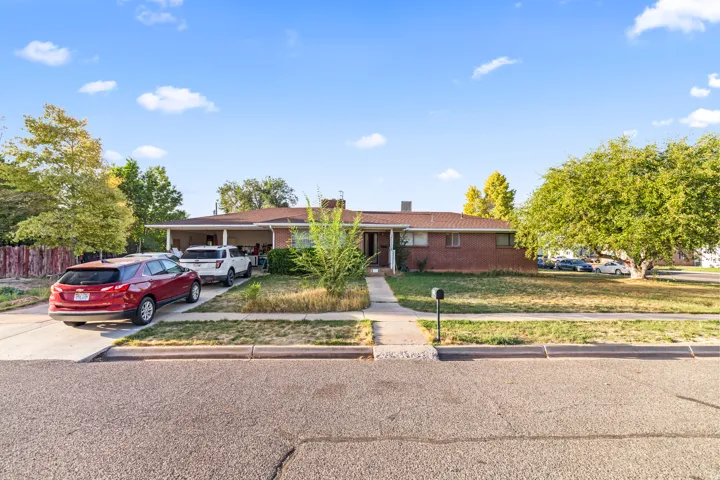 Brick exterior with a covered front porch, concrete driveway, and established front yard landscaping