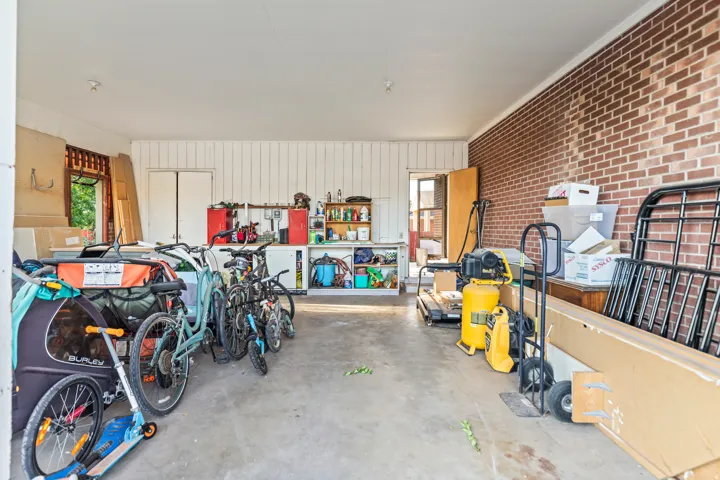 Attached garage featuring a concrete floor, exposed brick wall, and white paneled walls