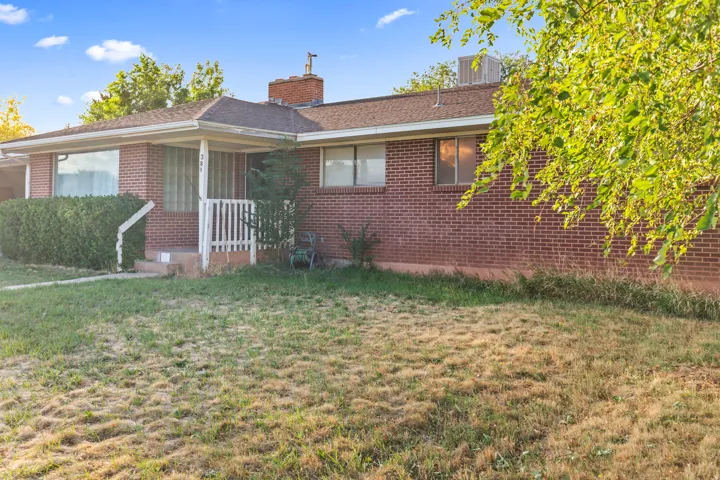 Brick exterior, covered entry, front porch with white railing, established shrubbery, multiple windows