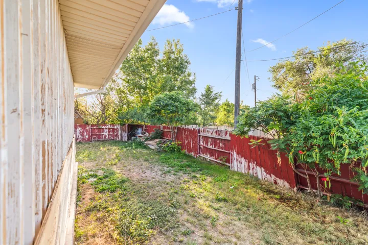 Enclosed backyard with a red-painted fence and natural landscaping