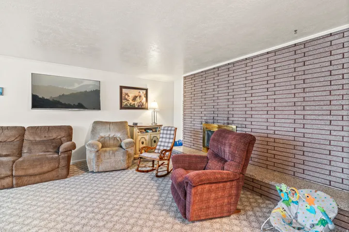 Brick fireplace with a brass firebox, wall-to-wall carpeting, and white painted walls