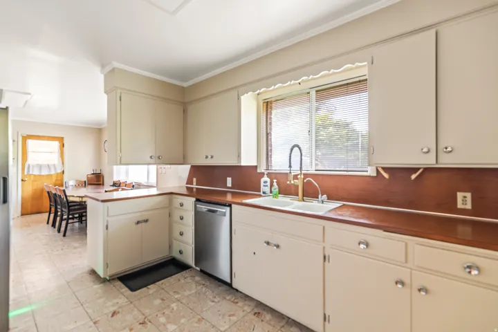 Kitchen featuring cream cabinetry, wood-finish countertops, tile flooring, and a stainless steel dishwasher