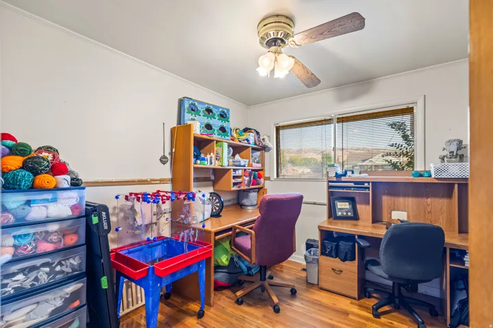 Wood-finish flooring, ceiling fan with integrated lighting, and a window with horizontal blinds