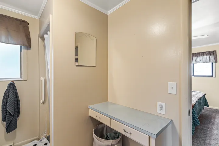 Vanity area with a built-in counter, integrated drawers, and a wall-mounted mirror