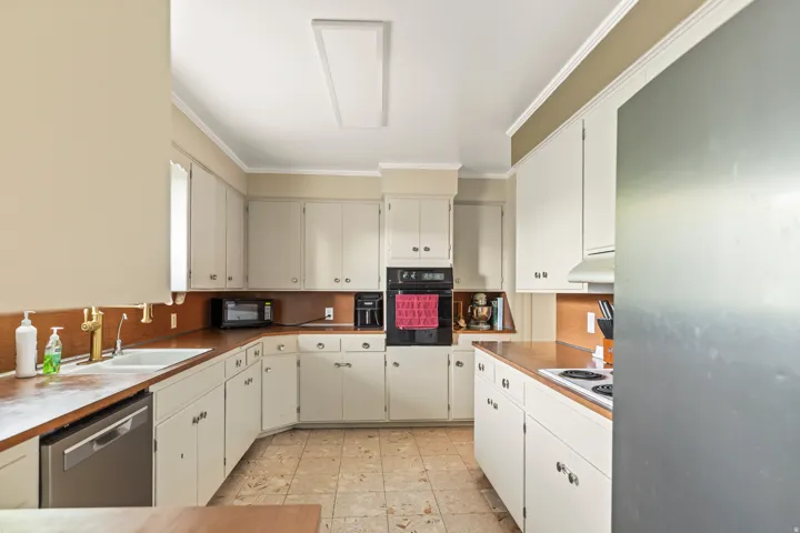 Kitchen with extensive cabinetry, wood-finish countertops, tile flooring, built-in wall oven, and recessed lighting
