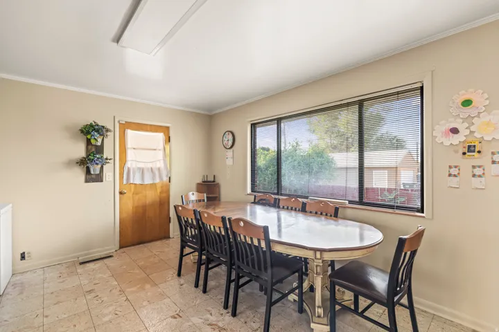 Light-toned tile flooring, large window with horizontal blinds, wood-finish door, and recessed ceiling lighting