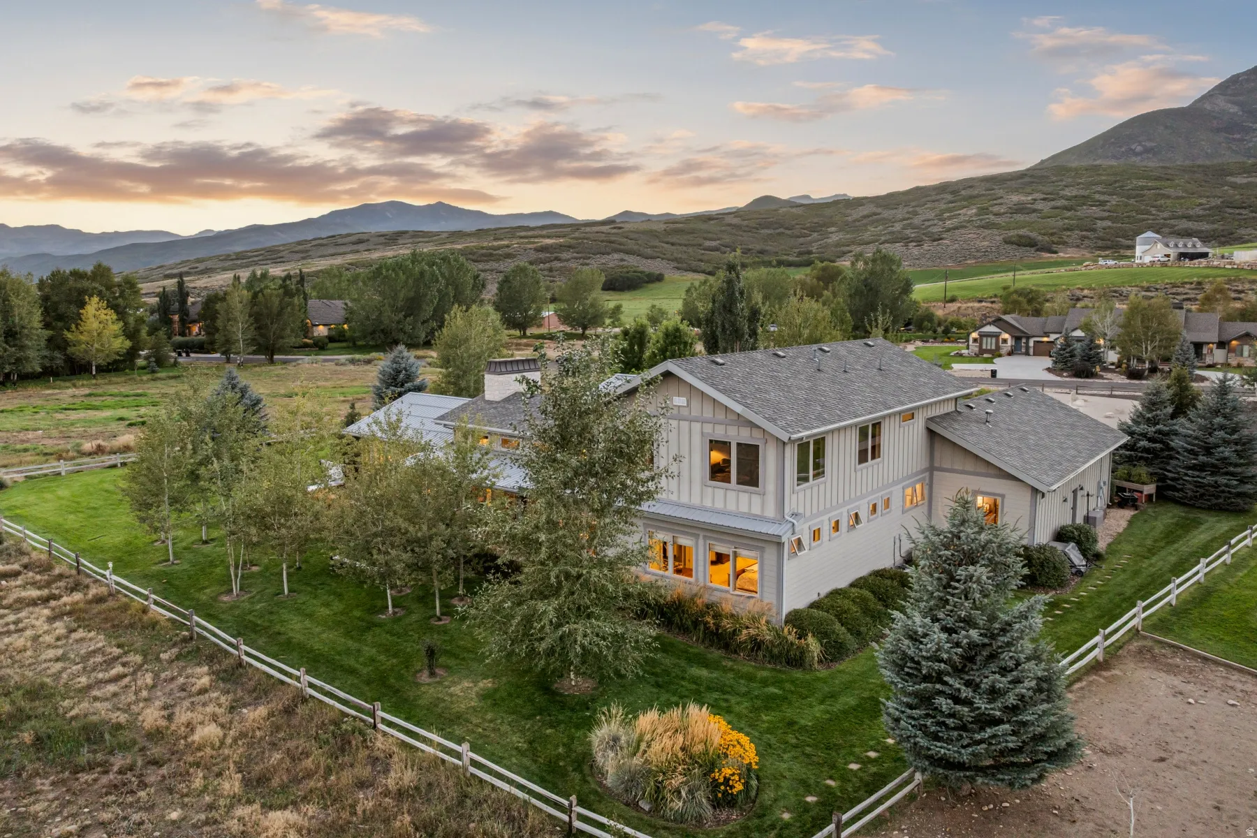 Contemporary-style architecture with multiple windows, a grey shingle roof, and a perimeter fence