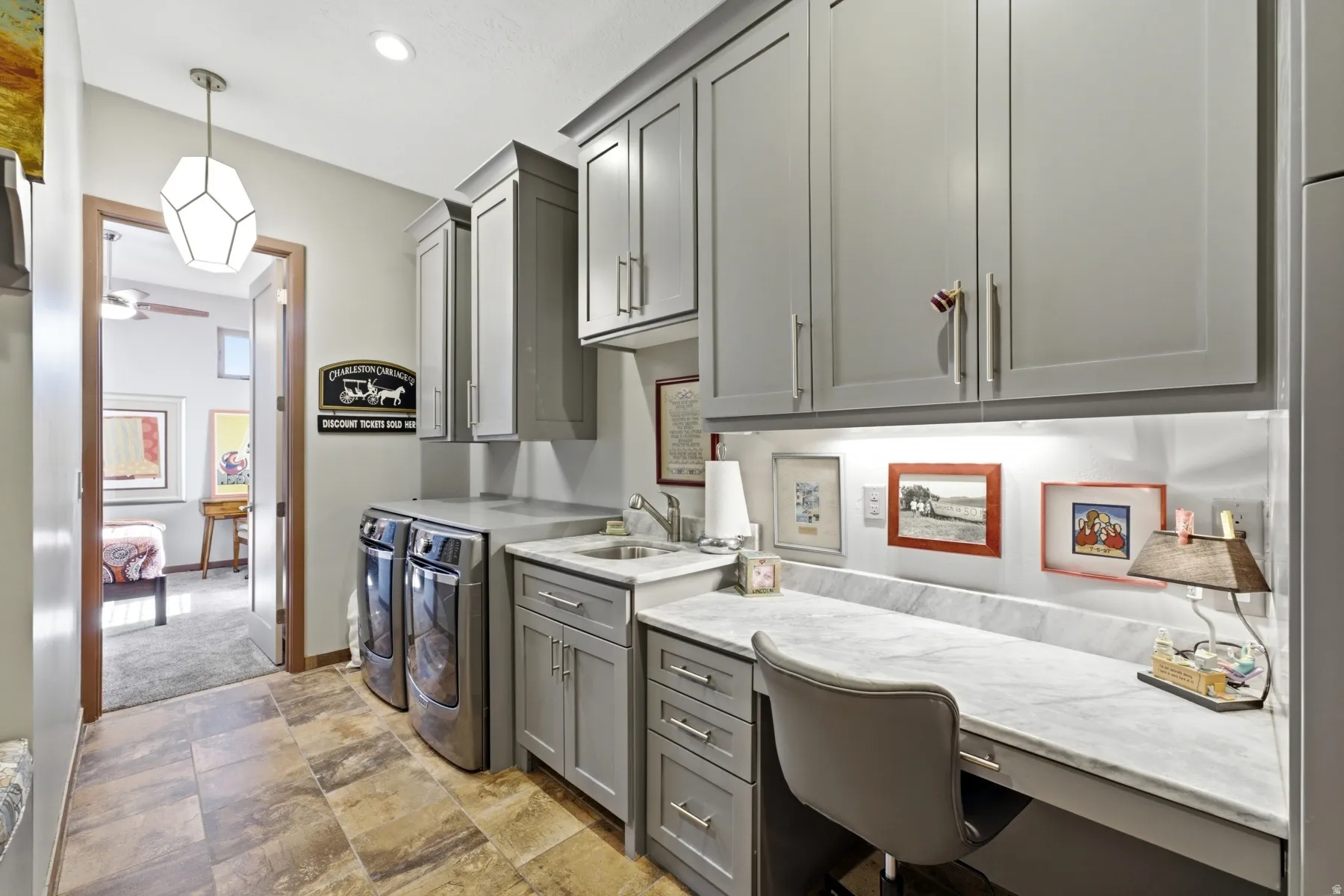 Integrated laundry space with built-in cabinetry, under-cabinet lighting, a utility sink, and a dedicated workspace with a stone countertop